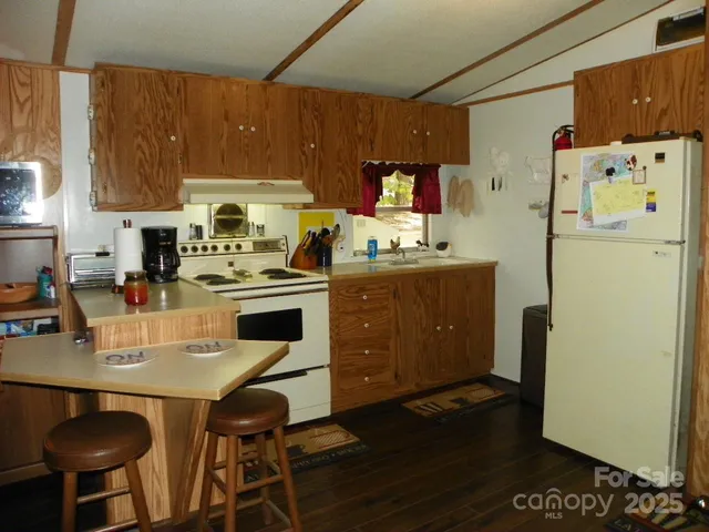 a kitchen with stainless steel appliances a stove a refrigerator a sink a dining table and chairs with wooden floor