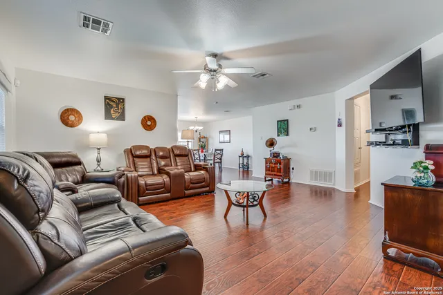 a living room with furniture kitchen view and a wooden floor