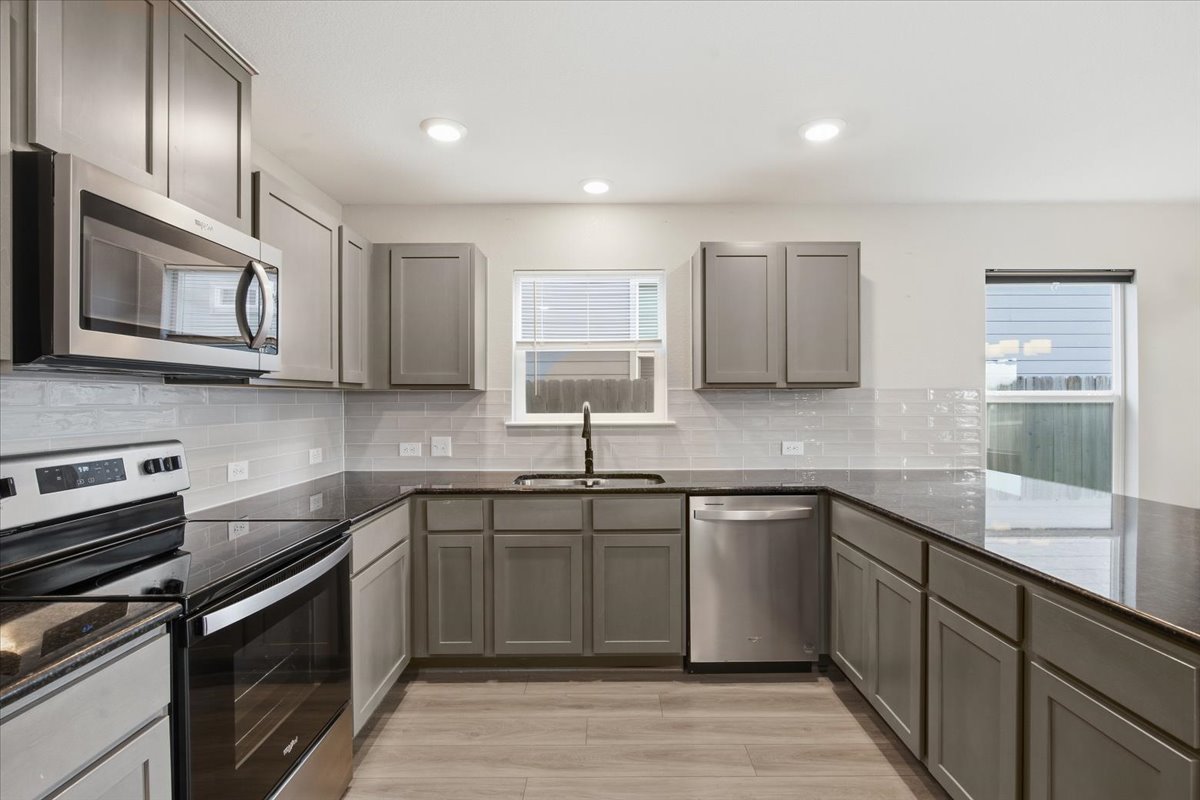 104 Rooster Way Jarrell, TX 76537 - Photo 13 of 33 Gleaming stone countertops and matching cabinetry surround a modern, functional workspace.