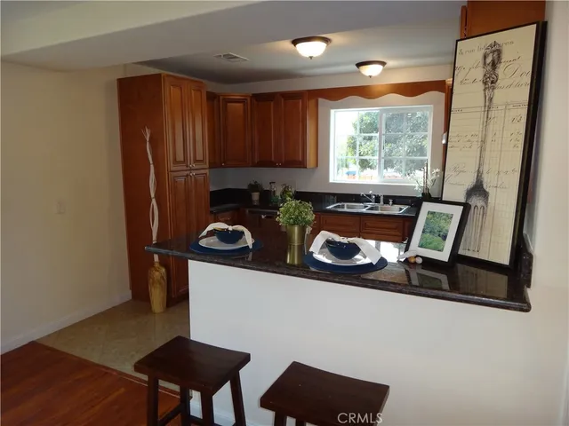 a kitchen with stainless steel appliances granite countertop a refrigerator a stove and a sink with wooden floor