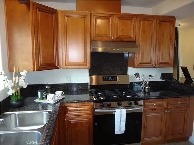 a kitchen with stainless steel appliances granite countertop a stove a sink dishwasher and cabinets with wooden floor