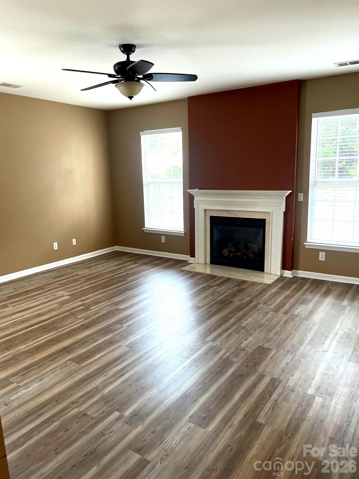 6006 Brook Valley Run Monroe, NC 28110 - Photo 10 of 27 an empty room with wooden floor fireplace and windows