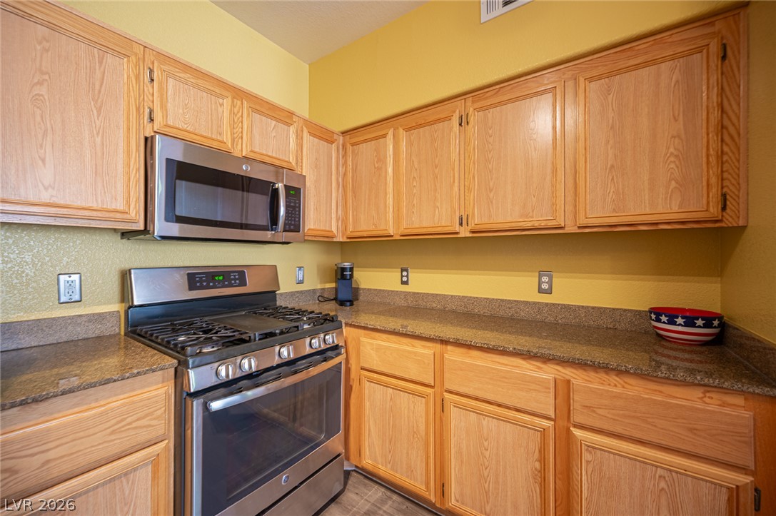 10550 West Alexander Road, Unit 2014 Las Vegas, NV 89129 - Photo 20 of 43 Ample wooden cabinetry offers plentiful storage above durable granite countertops.
