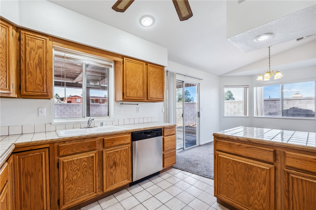 2524 South Ridge Avenue Bullhead City, AZ 86429 - Photo 23 of 64 Kitchen with dishwasher, a sink, vaulted ceiling, tile counters, and brown cabinetry