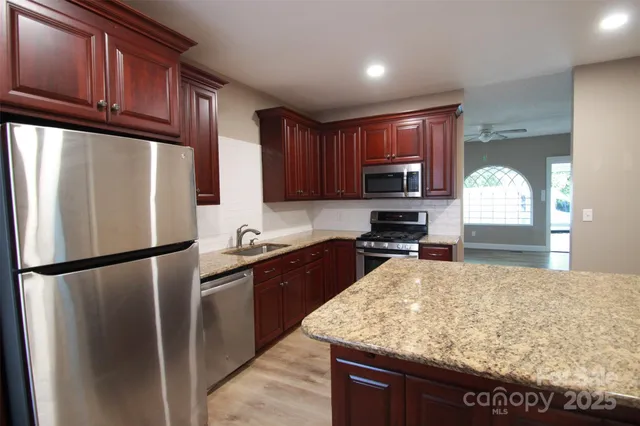 a kitchen with granite countertop wooden cabinets a refrigerator and a sink