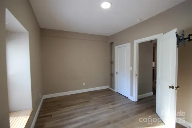 a view of an empty room with wooden floor and closet