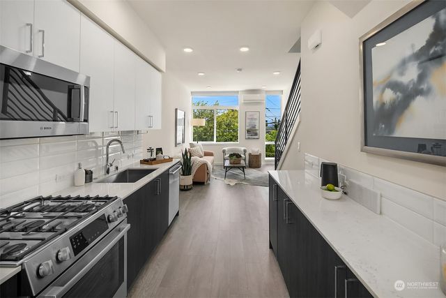 a large kitchen with stainless steel appliances granite countertop a lot of counter space and wooden floors