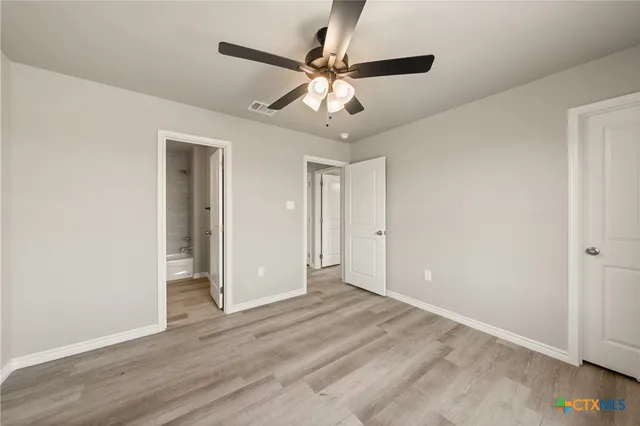 a view of an empty room and chandelier fan