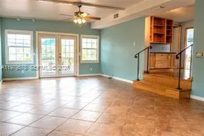 a view of an empty room with window and chandelier fan