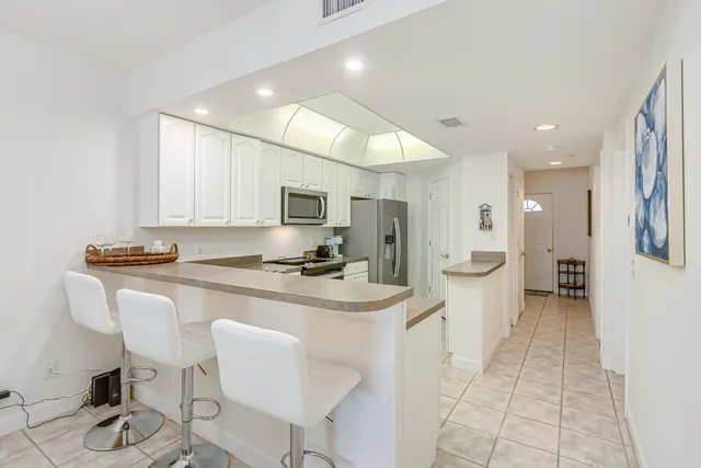 a spacious bedroom with a bed and a lamp on dresser