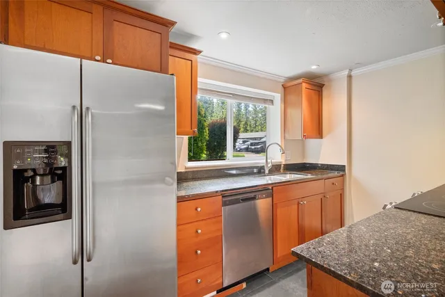 a kitchen with stainless steel appliances granite countertop a sink and a refrigerator