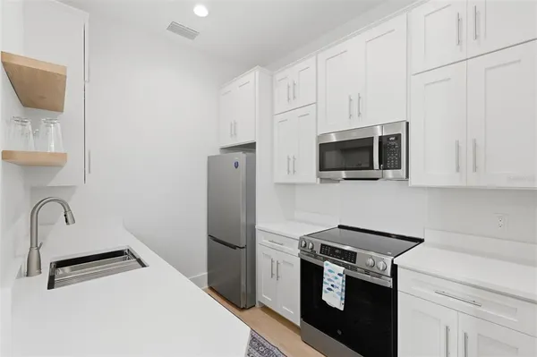 a kitchen with stainless steel appliances a stove microwave and sink