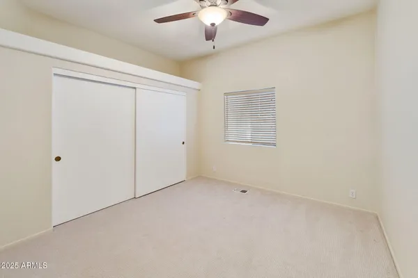 an empty room with a chandelier fan and windows