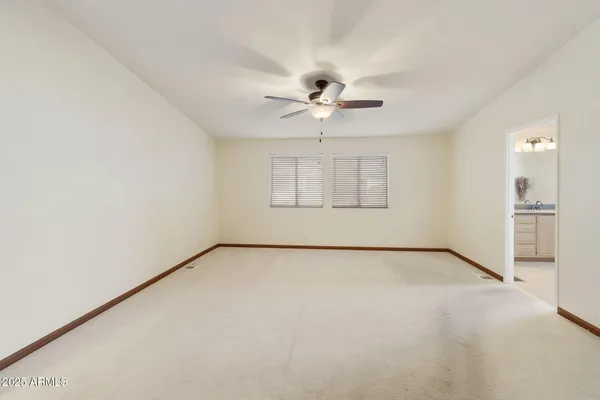 an empty room with chandelier fan and windows