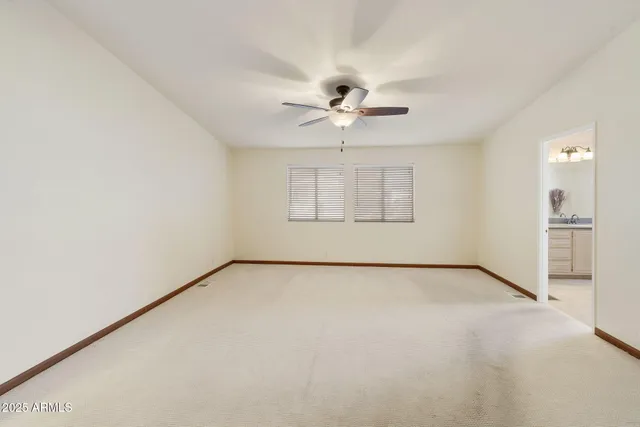 an empty room with chandelier fan and windows