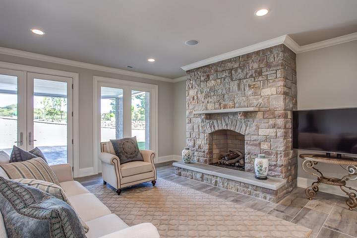 6664 Cross Keys Road College Grove, TN 37046 - Photo 22 of 29 LOWER LEVEL APT. Tiled flooring (looks like wood), large living area with stone gas fireplace, open to FAB kitchen, and to tiled stone covered patio to grass courtyard & pool.