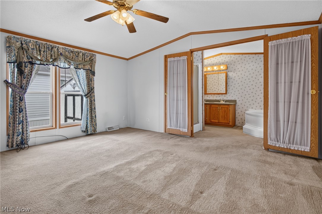 35157 Center Ridge Road, Unit 153 North Ridgeville, OH 44039 - Photo 25 of 35 Carpeted flooring, ceiling fan with light fixture, double windows, wood-paneled trim, and an adjacent bathroom with a wood-finish vanity