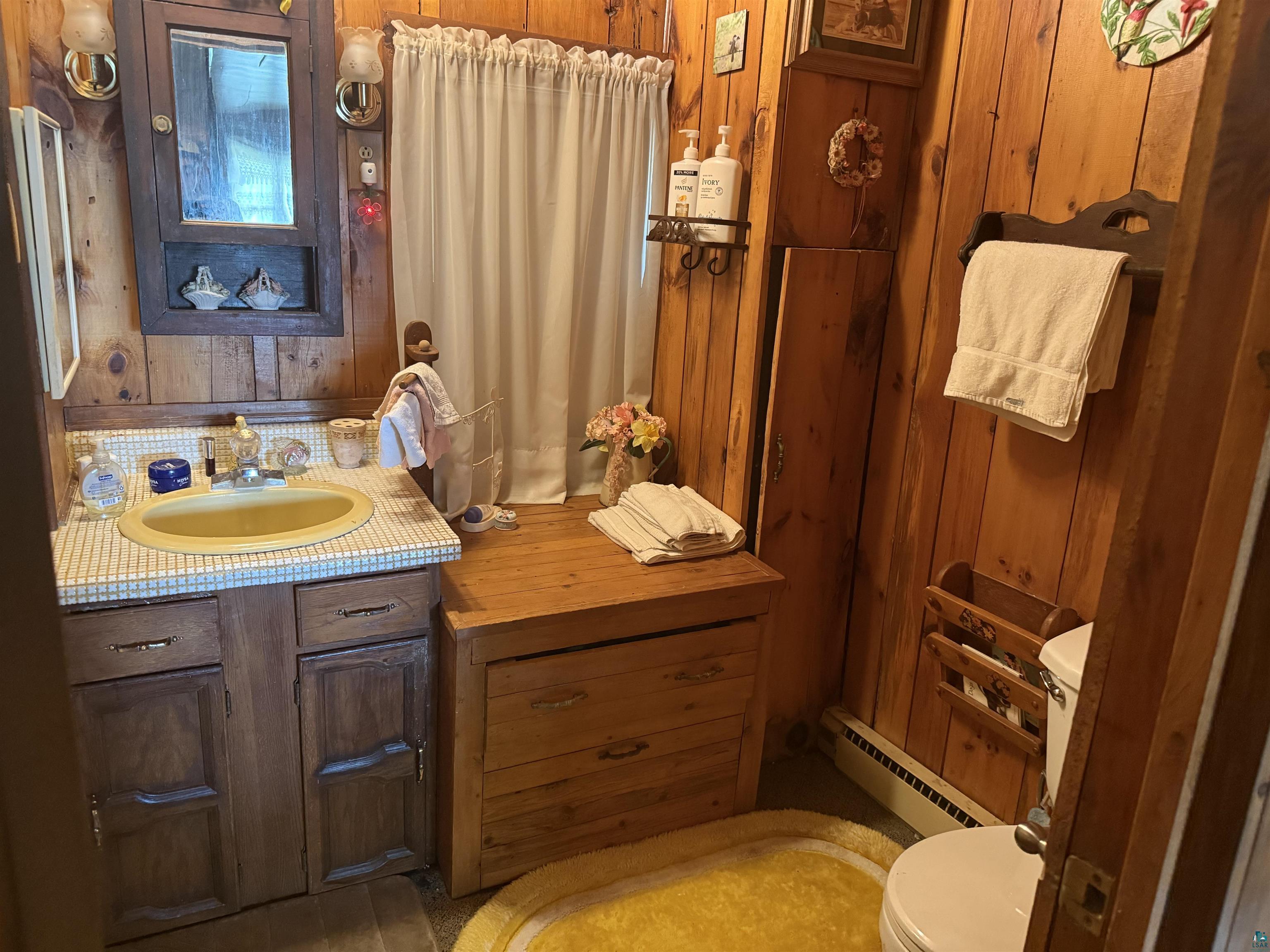 69175 East Long Lake Road Iron River, WI 54847 - Photo 13 of 47 Bathroom featuring baseboard heating, toilet, vanity, and wood walls