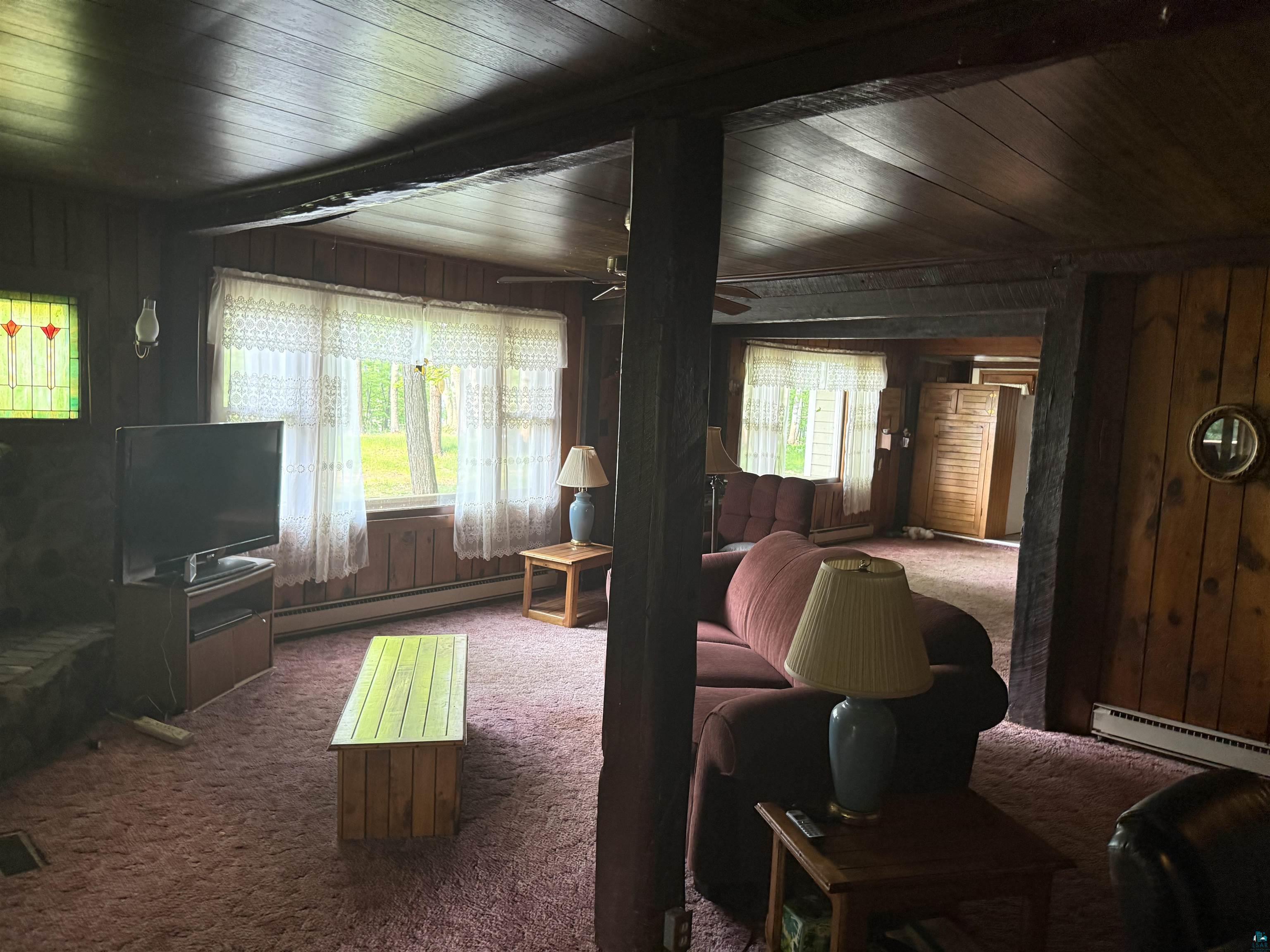 69175 East Long Lake Road Iron River, WI 54847 - Photo 5 of 47 Living area with carpet, a baseboard radiator, wood ceiling, wood walls, and ceiling fan