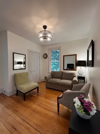 a living room with furniture chandelier and wooden floor