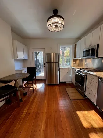 a kitchen with stainless steel appliances a stove a refrigerator and wooden floor
