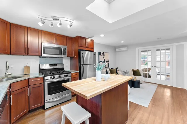 a large kitchen with stainless steel appliances a stove a refrigerator a sink dishwasher a dining table and chairs with wooden floor