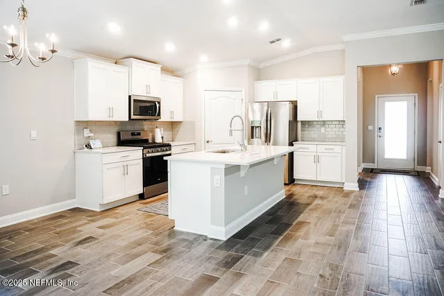 a kitchen with stainless steel appliances kitchen island granite countertop a stove top oven a sink a counter top space and cabinets