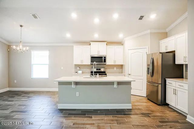 a view of kitchen with stainless steel appliances granite countertop a stove a refrigerator a sink and a microwave