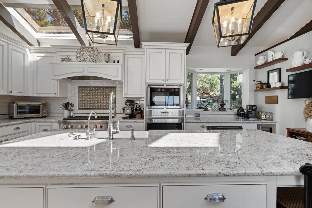 15 Mentone Road Carmel, CA 93923 - Photo 16 of 56 a kitchen with stainless steel appliances granite countertop a sink a stove counter space cabinets and a fireplace