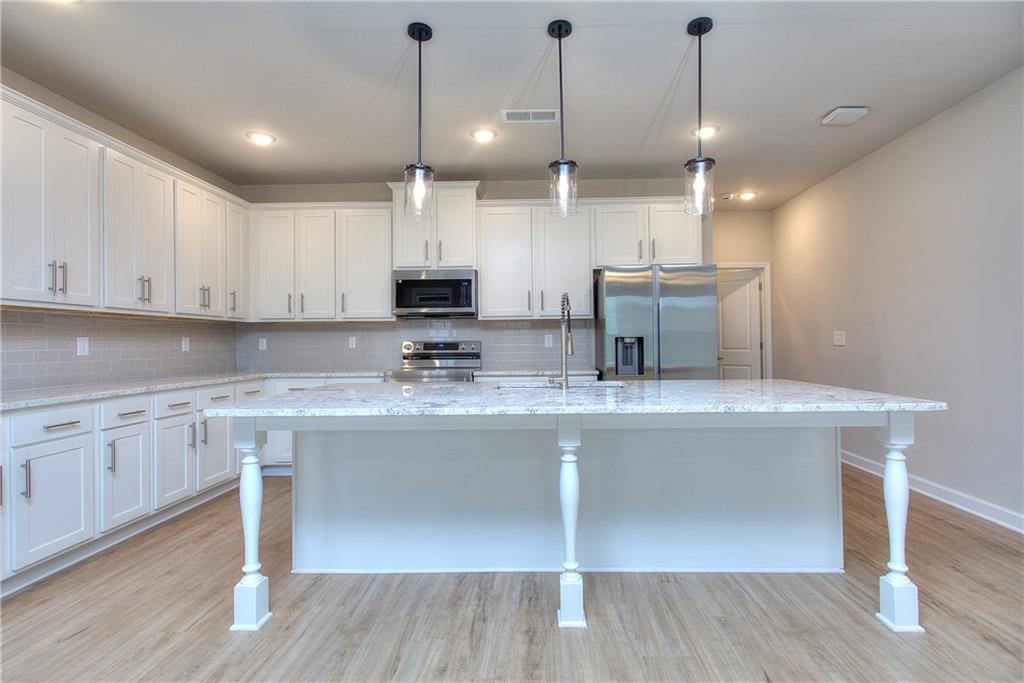 2562 Harbor Ridge Pass, Unit 338 Gainesville, GA 30507 - Photo 4 of 21 a kitchen with kitchen island granite countertop a sink a counter space appliances and cabinets