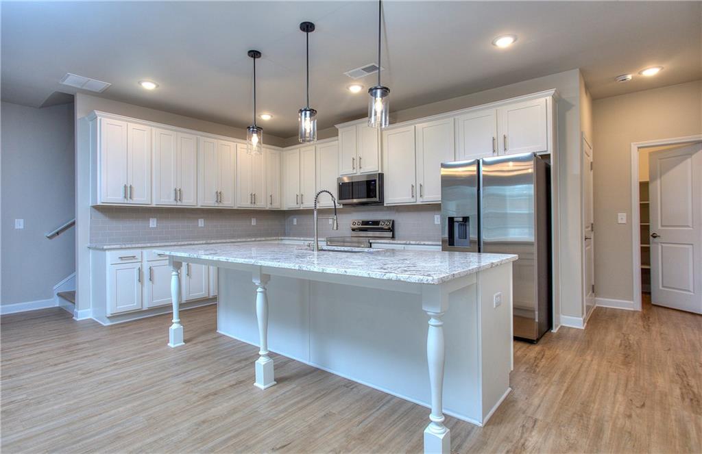 2562 Harbor Ridge Pass, Unit 338 Gainesville, GA 30507 - Photo 6 of 21 a kitchen with kitchen island granite countertop wooden floors appliances and cabinets