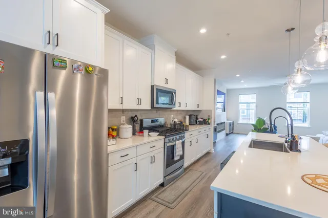 a kitchen with stainless steel appliances a refrigerator sink and white cabinets