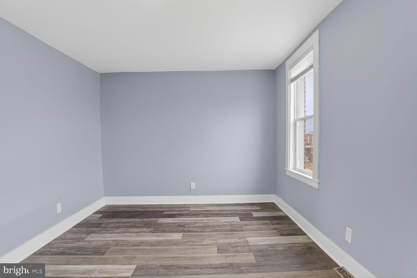 3335 Lyndale Avenue Baltimore, MD 21213 - Photo 6 of 9 a view of an empty room with wooden floor and a window