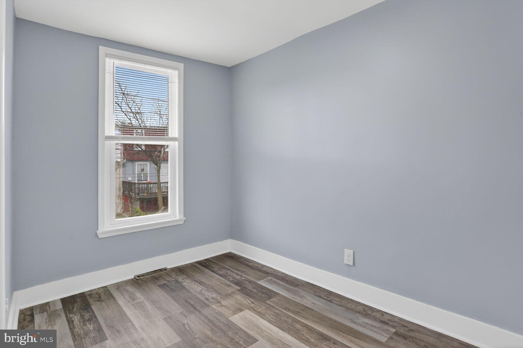 3335 Lyndale Avenue Baltimore, MD 21213 - Photo 7 of 9 a view of an empty room with wooden floor and a window