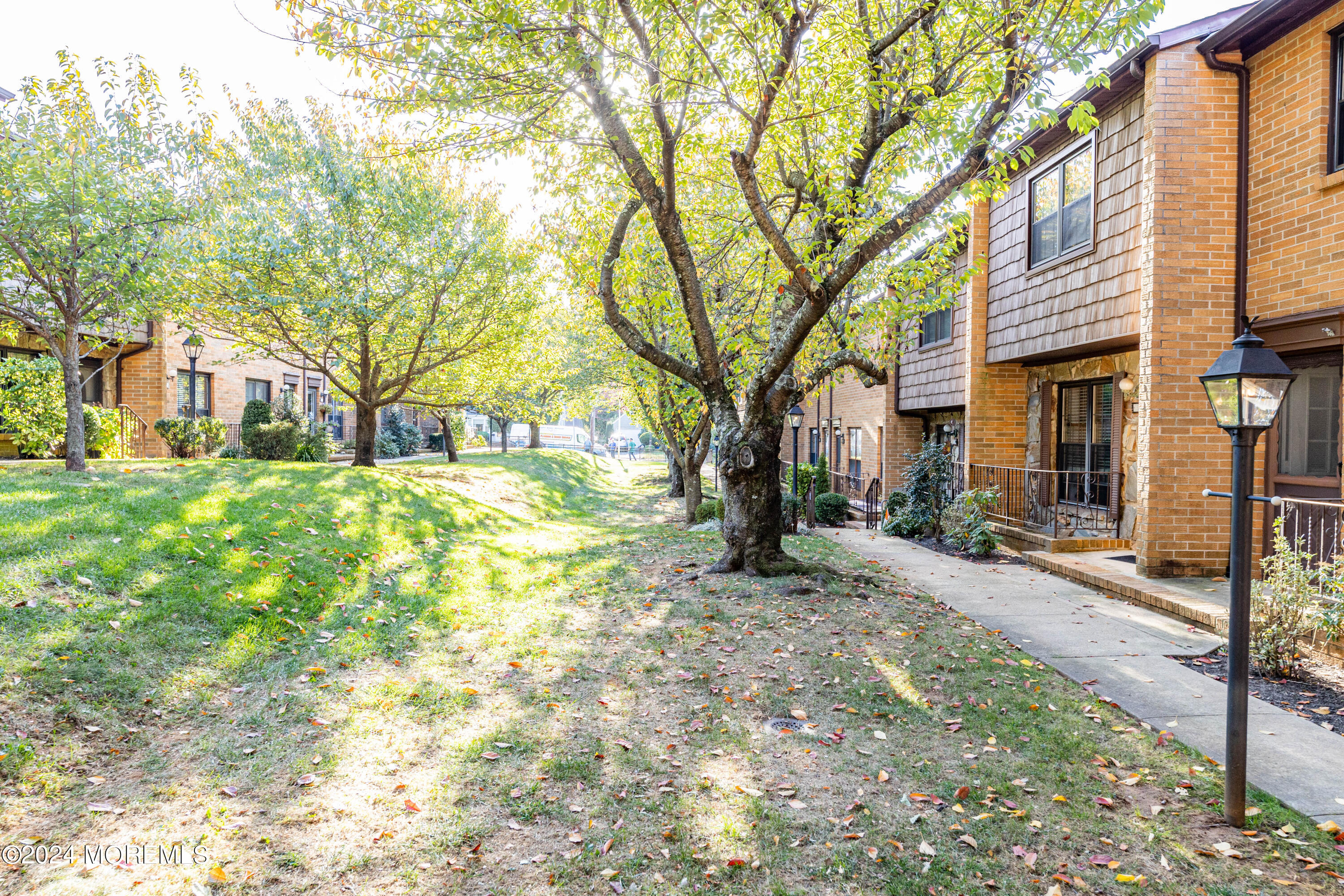301 Spring Street, Unit 11 Red Bank, NJ 07701 - Photo 2 of 40 a view of a yard with a house and trees in the background