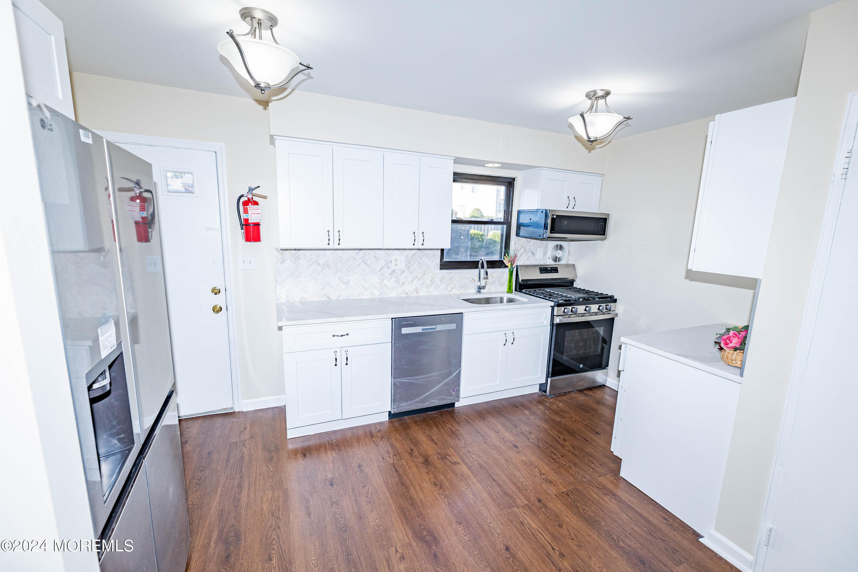 301 Spring Street, Unit 11 Red Bank, NJ 07701 - Photo 8 of 40 a kitchen with granite countertop a refrigerator a sink dishwasher a stove and white cabinets with wooden floor