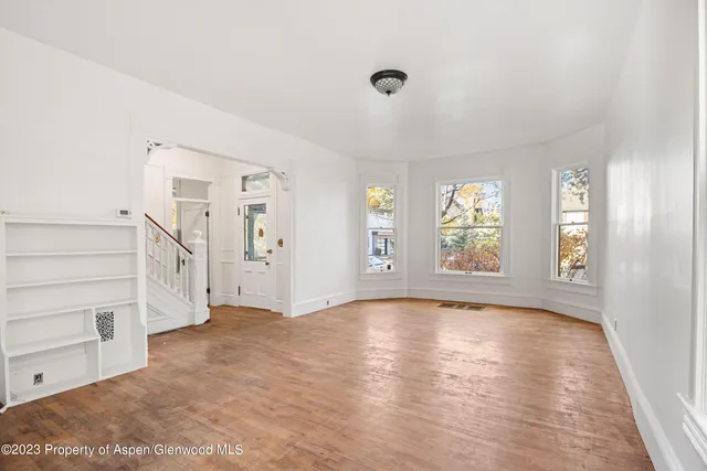 a view of an empty room with a window and wooden floor