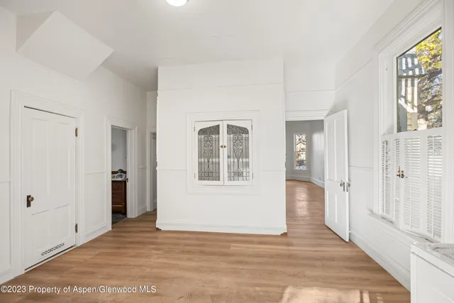 a view of an empty room with wooden floor and a window