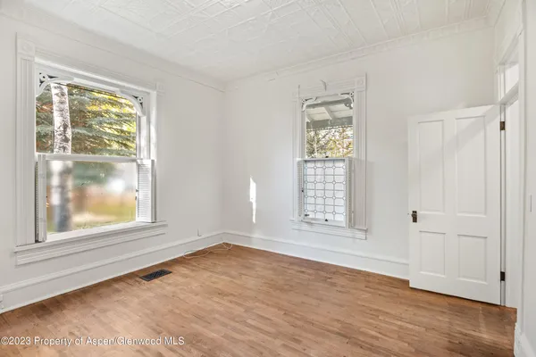 an empty room with wooden floor and windows