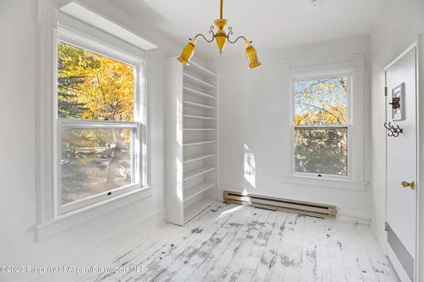 a view of an empty room with a window and wooden floor