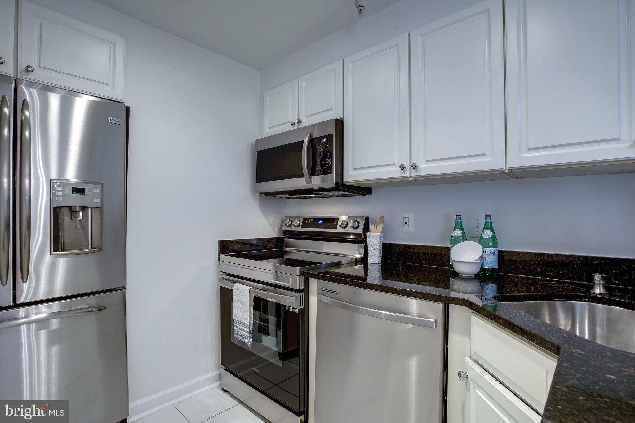 1619 R Street Northwest, Unit 404 Washington, DC 20009 - Photo 7 of 24 a kitchen with stainless steel appliances granite countertop a refrigerator a stove a microwave and cabinets