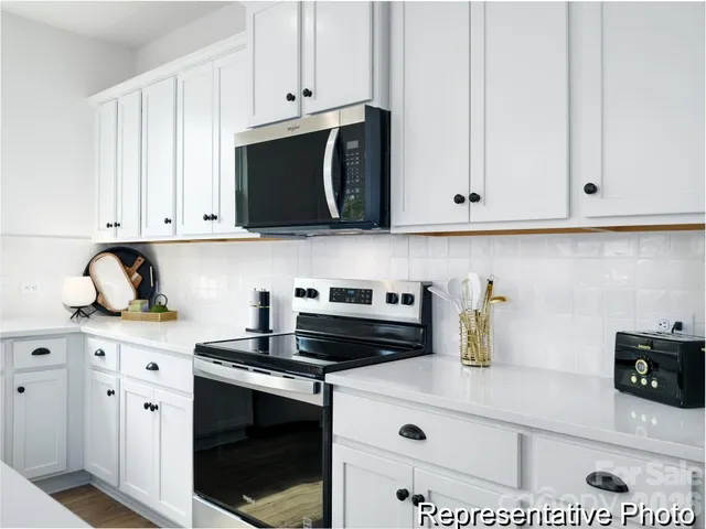 a kitchen with stainless steel appliances granite countertop white cabinets and a stove a oven with white countertops