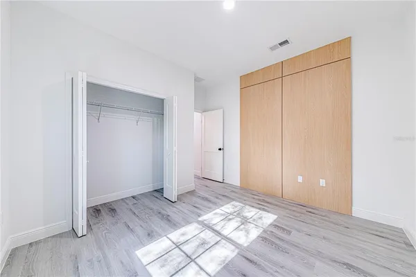 an empty room with wooden floor and closet