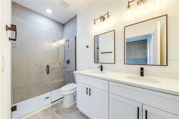 a bathroom with a double vanity sink toilet mirror and shower