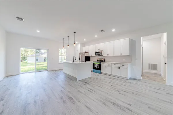 a large kitchen with white cabinets and wooden floor