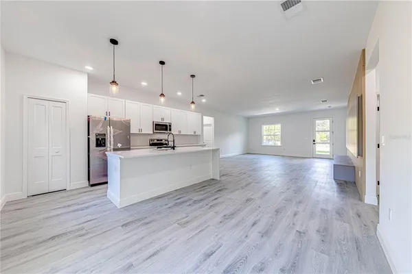 a view of kitchen with kitchen island wooden floor center island and stainless steel appliances