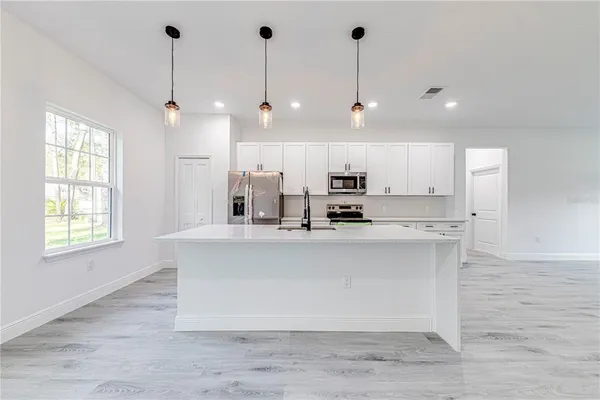 a large kitchen with granite countertop a large counter top a sink stainless steel appliances and cabinets