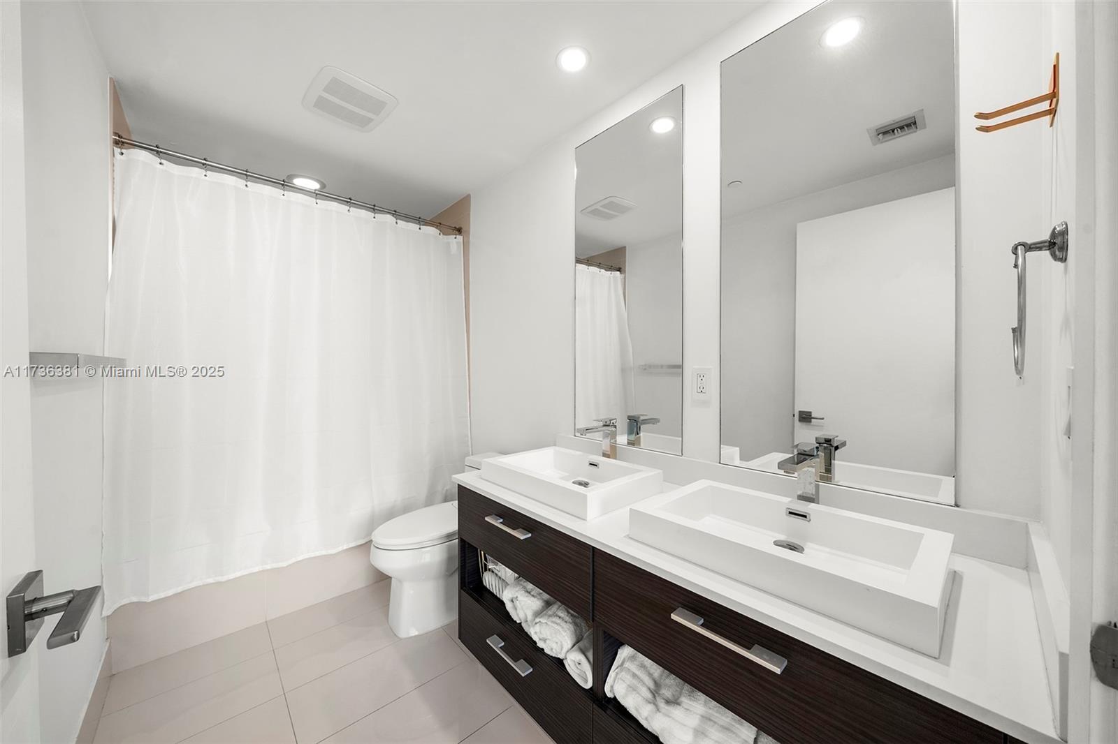 55 Southwest 9th Street, Unit 1701 Miami, FL 33130 - Photo 16 of 58 a bathroom with a double vanity sink toilet and a mirror