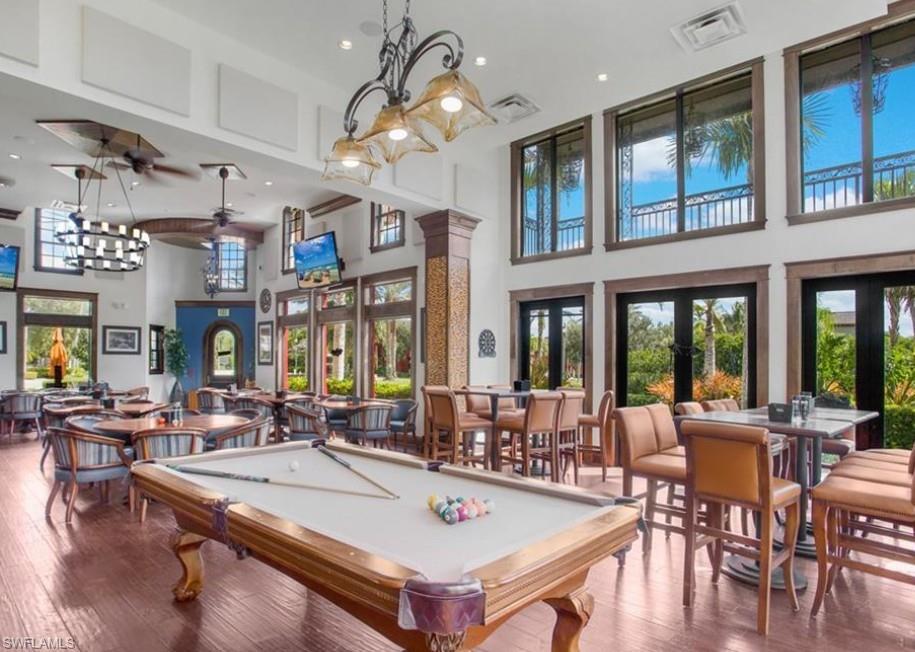 9050 Capistrano Street North, Unit 4102 Naples, FL 34113 - Photo 19 of 31 a view of a dining room with furniture a chandelier and large windows