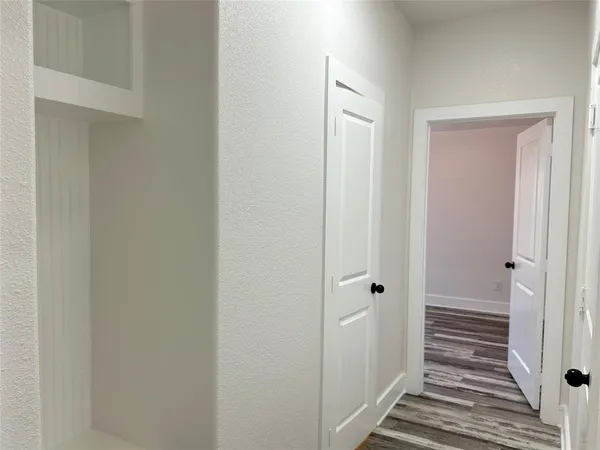 a view of a hallway with wooden floor and closet